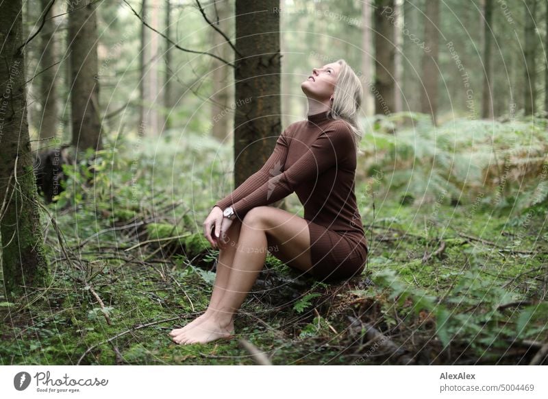 Young blonde woman sitting barefoot on fallen tree trunk in forest looking at sky Young woman Woman Blonde Feminine pretty fortunate Youth (Young adults)