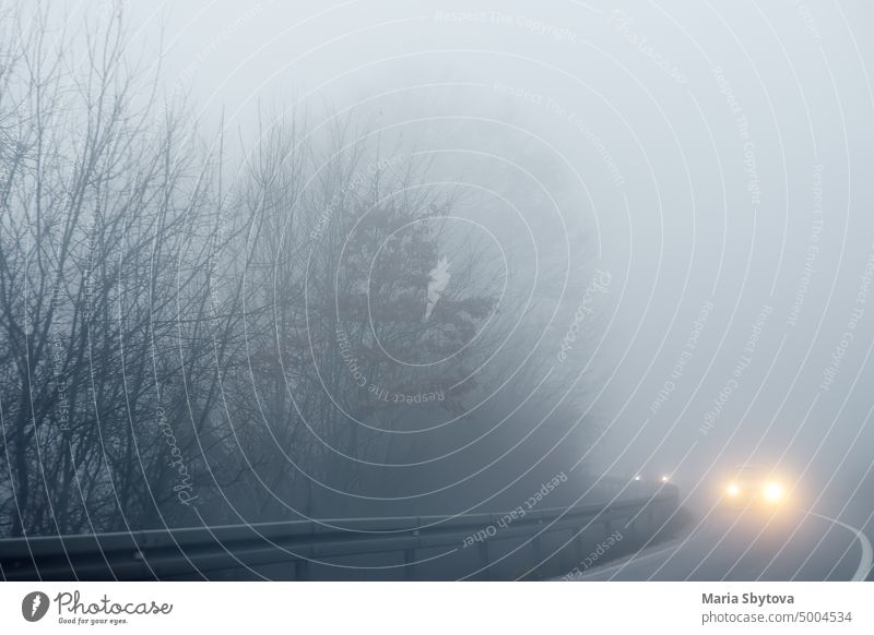 Thick fog on the highway in Europe on a winter day. The danger of driving of vehicles on roads in bad foggy weather. Insurance of safety of drivers and cars.