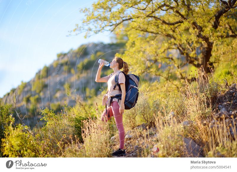 Young woman hiking in mountains in Europe at summer. Sunset landscape of hills. Concepts of adventure, extreme survival, orienteering. hike water drink bottle