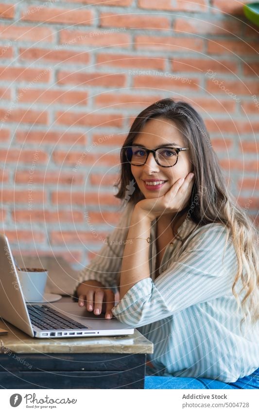 Smiling female freelancer using laptop in cafe woman smile project happy data delight remote telework table glad young smart casual workplace busy cafeteria