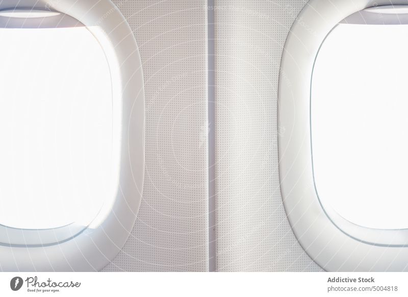 Windows of modern plane in daytime window sunlight illuminate white cabin interior aviation flight design contemporary transport glass bright daylight symmetry