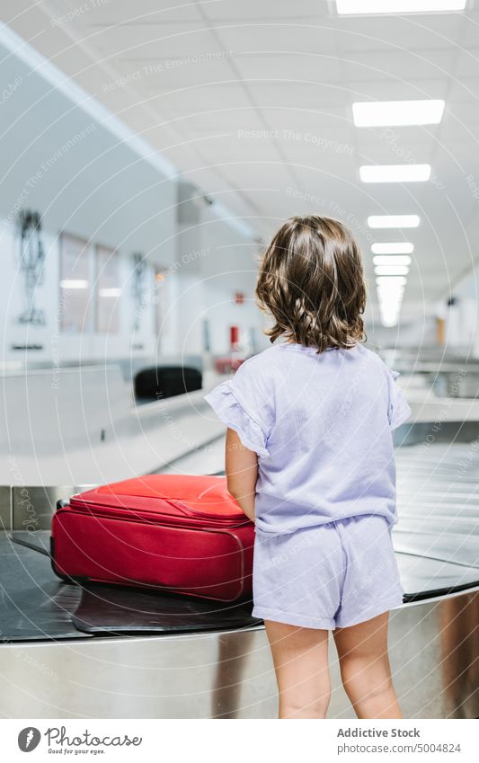 Anonymous girl in airport terminal wait travel carousel luggage belt vacation arrive passenger trip tourist holiday baggage child tourism transit contemporary