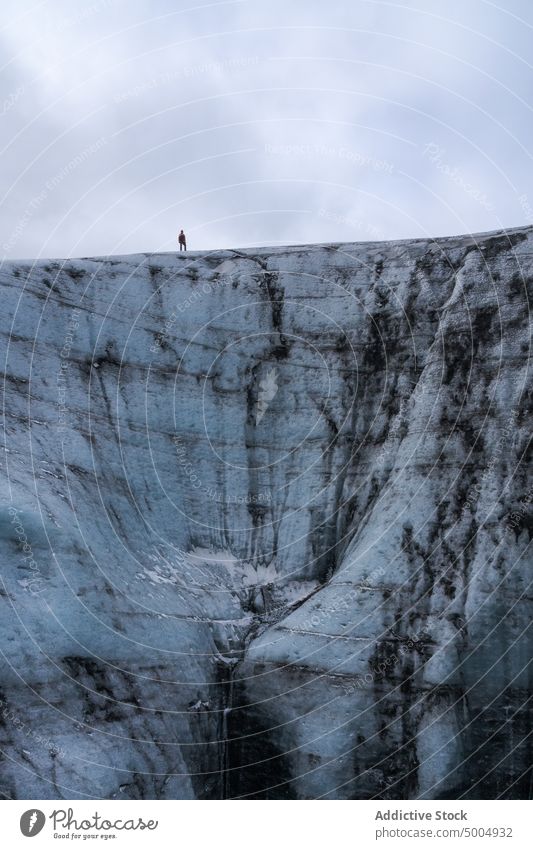 Ice formation with tourist in winter glacier ice traveler cold cloudy sky gray frozen iceland vatnajokull national park climate uneven overcast rough polar