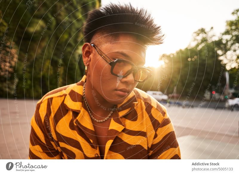 Trendy guy in sunglasses at sunset in city man non binary trendy urban cool street style lgbtq dusk sunlight earring queer asian filipino unaltered sundown