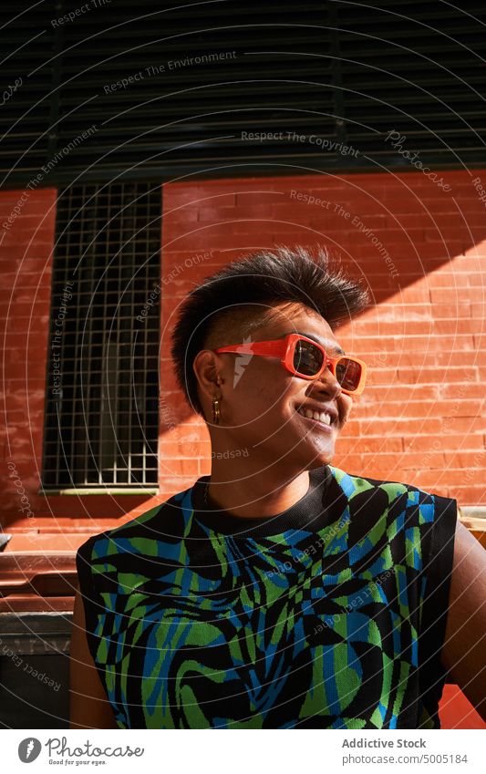 Cheerful Asian transgender woman against brick wall smile happy urban non binary style street appearance asian filipino ethnic unaltered natural beauty