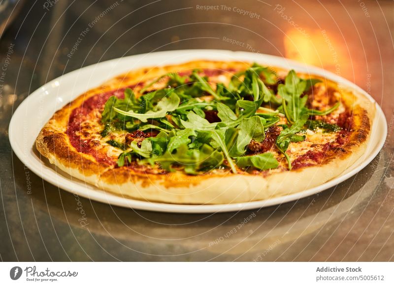 Tasty pizza with arugula leaves plate lunch serve leaf herb table pizzeria tradition italian cuisine dish food palatable yummy tomato pesto parmesan delectable