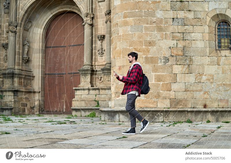 Hipster tourist examining map near old building man orientate direction hipster tourism navigate medieval aged traveler street town trip male journey style