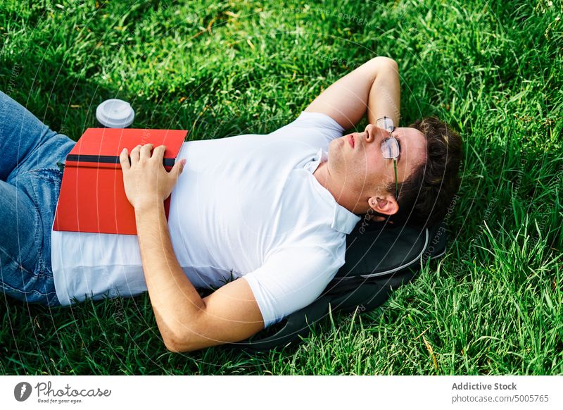 Student relaxing with closed eyes on grass student campus rest lying sleep break man lawn male meadow nature park summer carefree recreation university enjoy