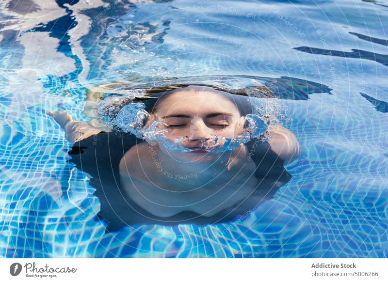 Woman swimming in blue pool woman underwater refreshment bubble summer emerge holiday enjoy young female vacation resort activity recreation summertime aqua