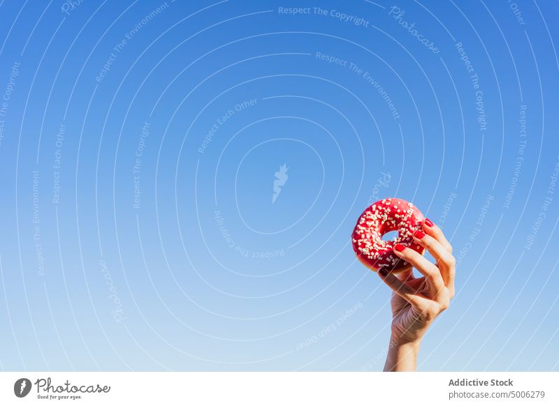 Woman with pink donut in summer day hand blue sky colorful woman sweet tasty food dessert female delicious yummy sprinkle treat pastry show demonstrate snack