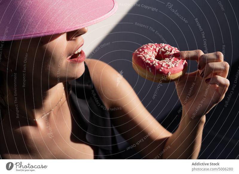 Happy woman eating donut on poolside enjoy pink summer sunlight color inflatable carefree young female mattress delicious doughnut recreation relax chill