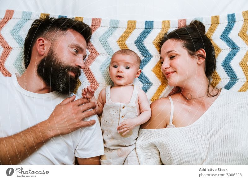 Happy parents having fun while relaxing with infant together on bed family baby make face adorable father mother teasing love child happy fondness cuddle