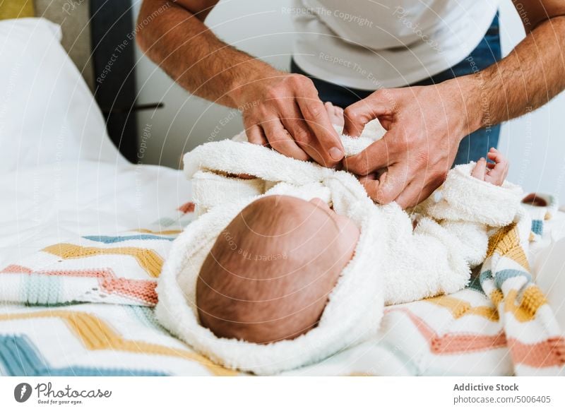 Crop father clothing baby in warm robe after bathing in light bedroom relax bathrobe dressing fresh hand parent parenthood infant kid home dad child care