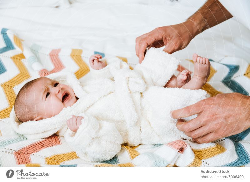 Crop father clothing baby crying in warm robe after bathing in light bedroom relax bathrobe dressing fresh hand parent upset parenthood infant kid home dad