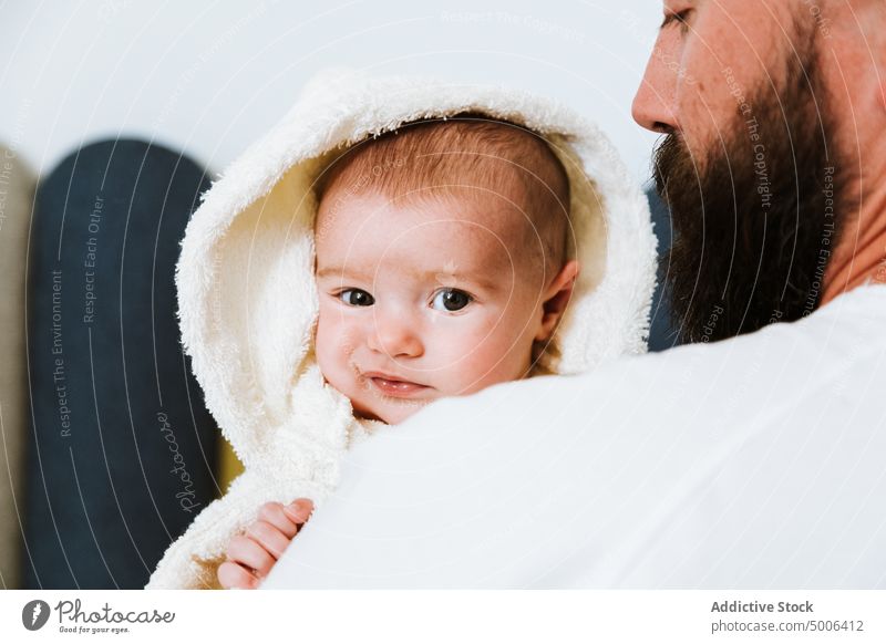 Calm adult father carrying cute baby on hands at home parent dad child wash fresh shower bathrobe infant curious relationship tranquil smile fondness fatherhood