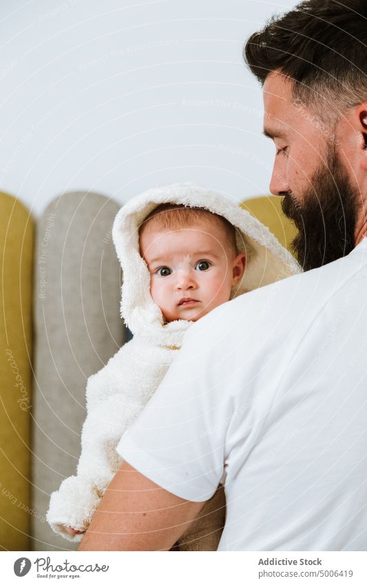 Calm adult father carrying cute baby on hands at home parent dad child wash fresh shower bathrobe infant curious relationship tranquil smile fondness fatherhood