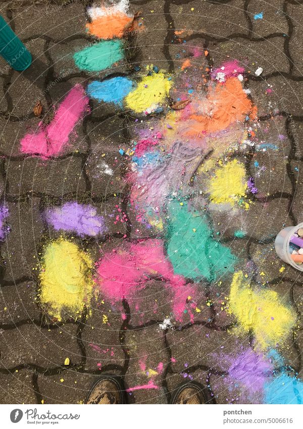 Colorful squished patches of sidewalk chalk on cobblestones. Colorful children's game street chalk blotch Children's game variegated colors Infancy Creativity