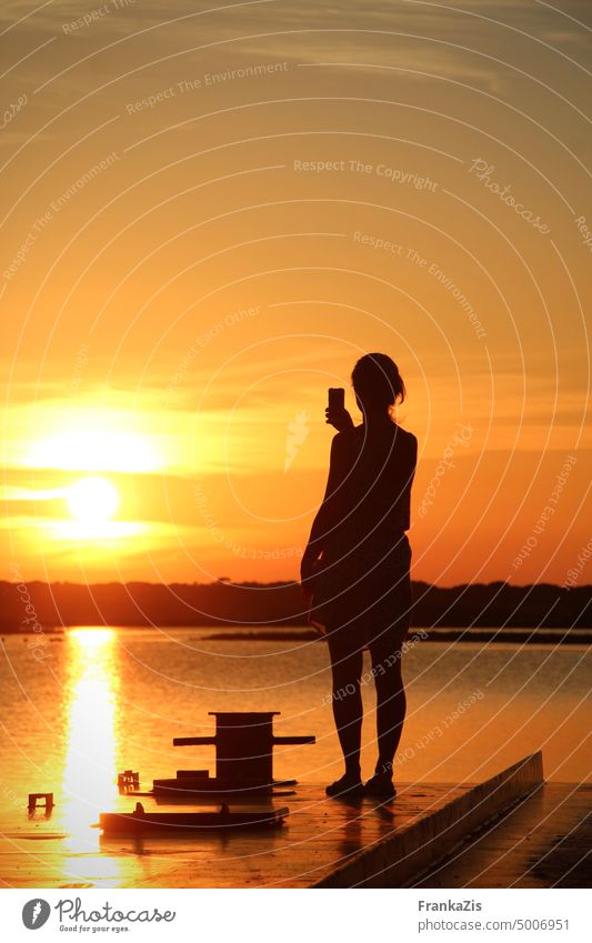 Woman photographing sunset over lagoon with her smartphone Sunset Evening Sky Water Dusk Light Take a photo Capture moment Summer Nature Exterior shot Sunlight