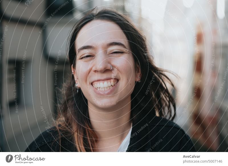 Portrait of cheerful caucasian woman looking at camera smiling standing on the city street with cinematic tones. Happy emotions.Young cheerful woman big smile on the street.