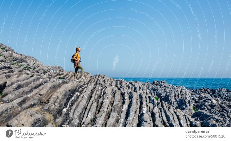 Woman with backpack walking through flysch rock landscape woman copy space young adult trekking hiking seascape people nature camera travel active girl person