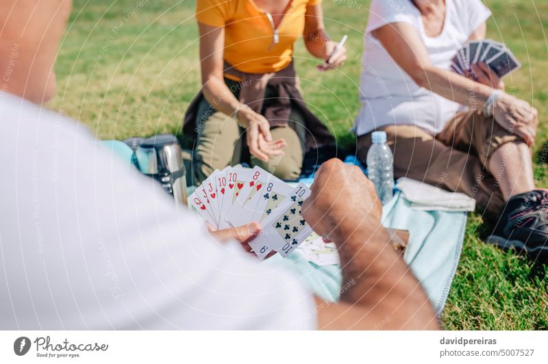 Unrecognizable adult family playing cards during an excursion unrecognizable picnic poker senior hand together parent daughter deck sitting group friend blanket