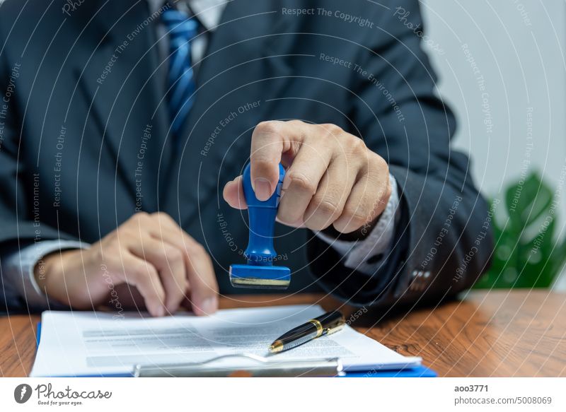 Man stamping approval of work finance banking or investment marketing documents on desk. rubber man paperwork agreement office authority ink business