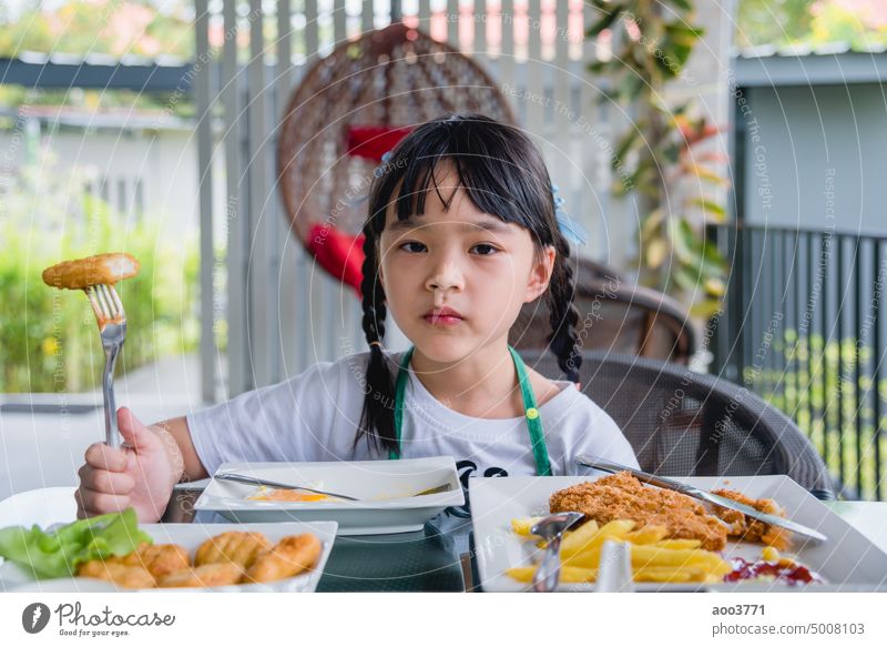 Asian young girl Eating Chicken nuggets fast food on table. chicken person child photography one person female color image portrait woman indoor enjoyment