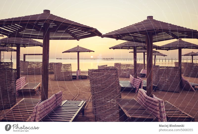 Beach with sun beds, umbrellas and windscreens at sunrise, color toning applied, Egypt. vacation beach peaceful nature sea summer sunset silhouette getaway