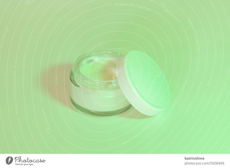 Opened Cosmetic jar with a lid close up, mockup. Green light. Everyday skincare routine cream cosmetics green hard shadow white negative space copy space Brand