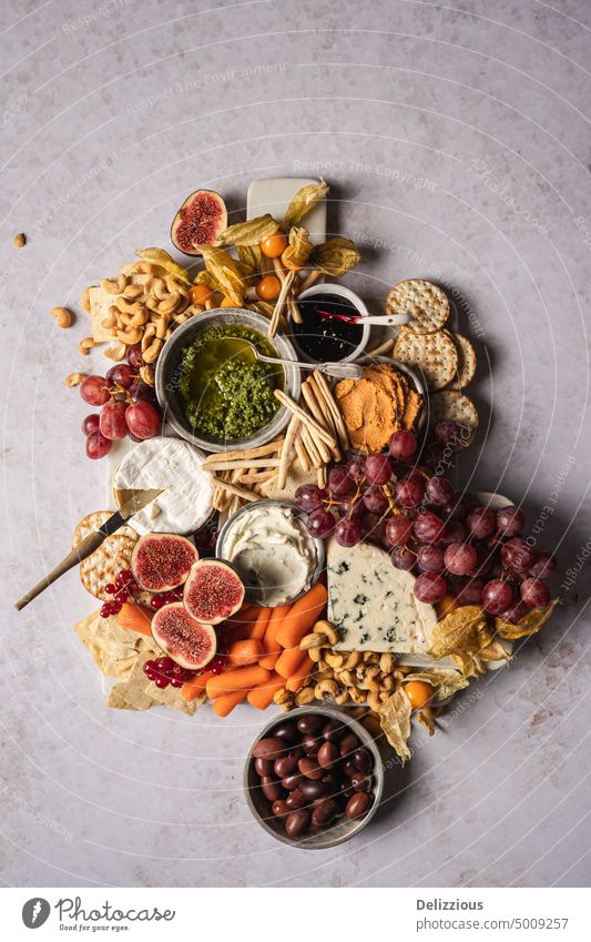 A beautiful cheese platter board with fruit, vegetables, dips and nuts on a white background, vertical antipasto camembert carrots cheese board cheeseboard