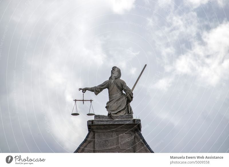 A statue of Justice with sword and scales from behind on a pedestal Lady Justice Statue Sword Scale Balance Law fair Goddess goddess of justice Arrangement
