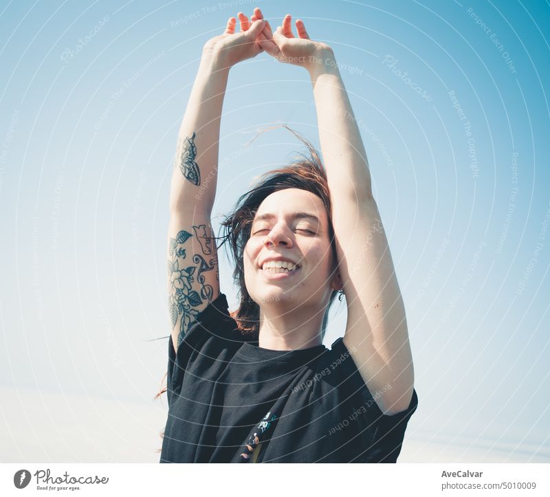 happy young woman enjoying freedom raising arms to the sky while closing eyes. Blowing hair and relax, Liberty and future concept person raised sunrise up