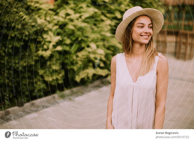 Young woman with hat walking in the resort garden female vacation beach luxury happy beautiful sunny young tourism holiday summer nature relax travel dress