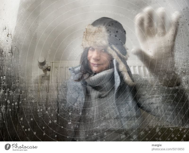A woman sits in front of a heater with thick winter clothes and looks through the fogged window Woman Heating Energy Winter Save energy Window Window pane