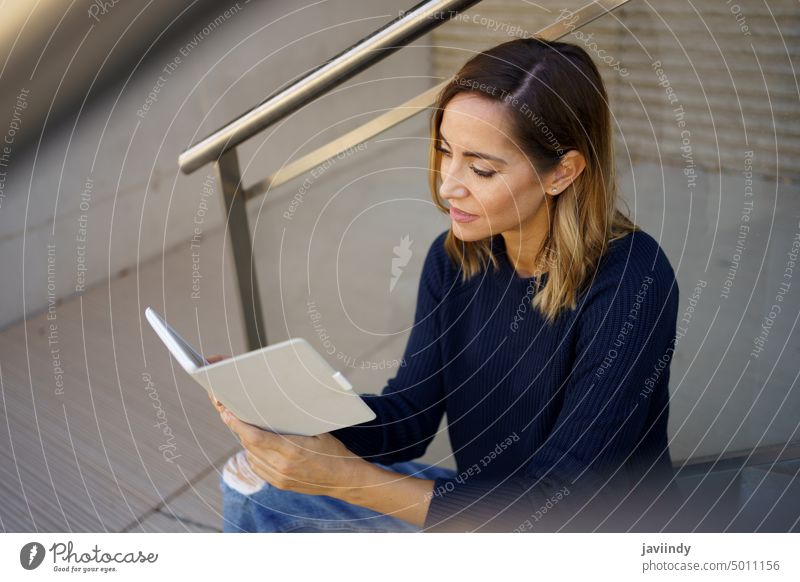 Middle-aged woman reading with her e-book on a coffee break near her office. ebook middle aged caucasian urban lifestyle technology copy space copyspace female