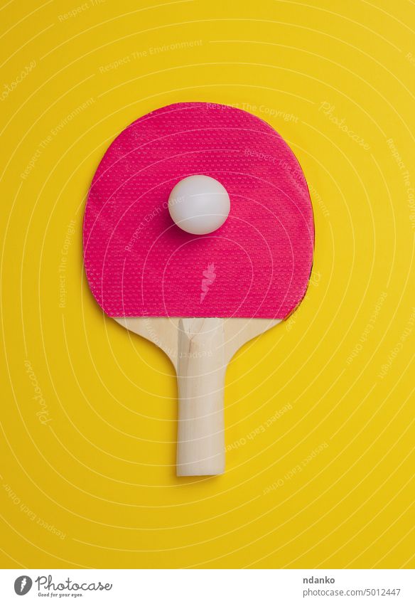 Wooden ping pong tennis racket and plastic ball on yellow background sport game equipment leisure competitive paddle play recreation wood challenge handle