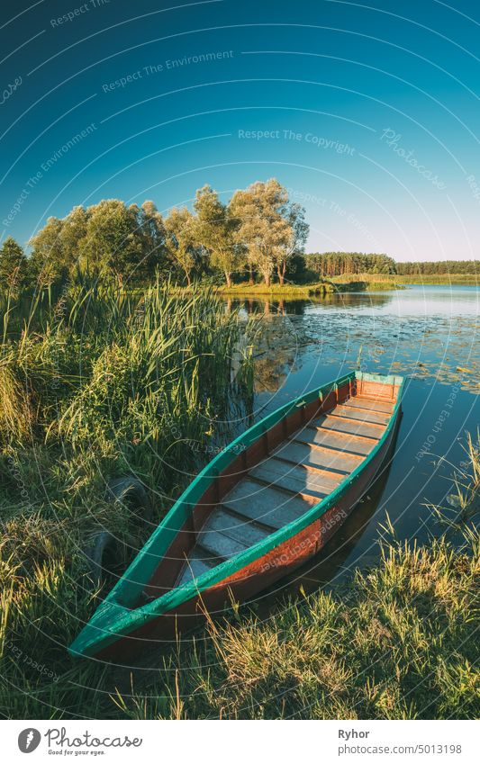 Old Wooden Rowing Fishing Boat Near Lake Or River Coast At Beautiful Summer Sunny Day. Typical Nature Of Belarus Or Western European Part Russia row boat