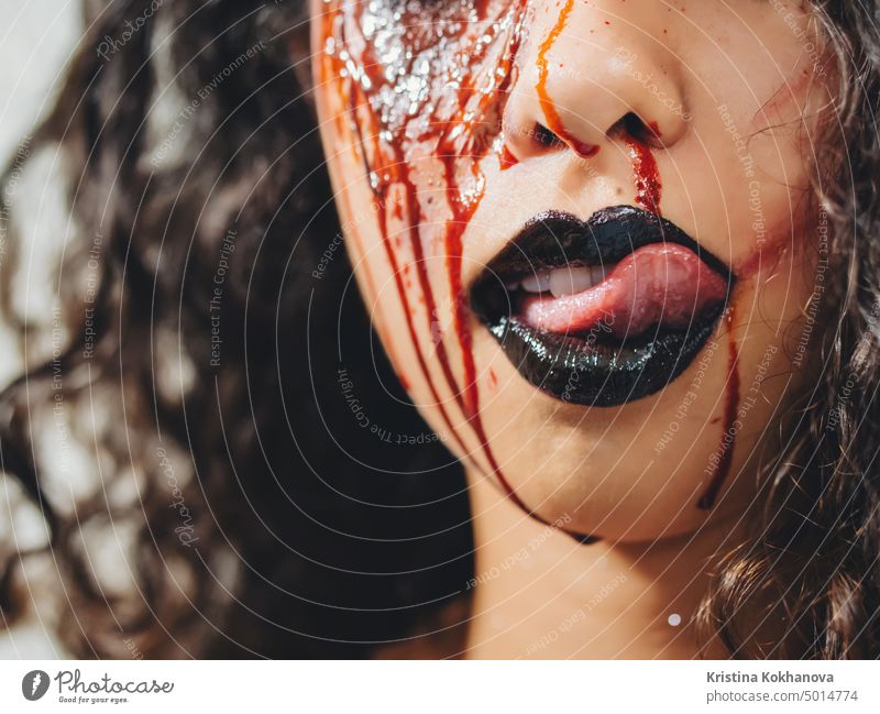 Scary portrait of young zombie woman with Halloween blood makeup. Beautiful latin beaten girl with curly hair looking into camera. adult art artist beautiful