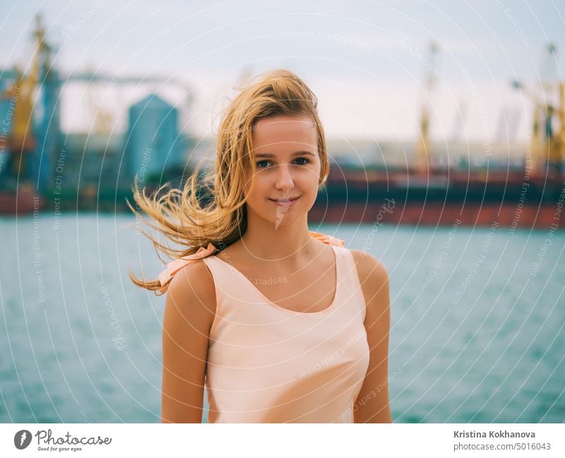 Portrait of young girl hipster beautiful blonde teenager smiling and posing in marine port at windy summer day. attractive background beauty caucasian cute face