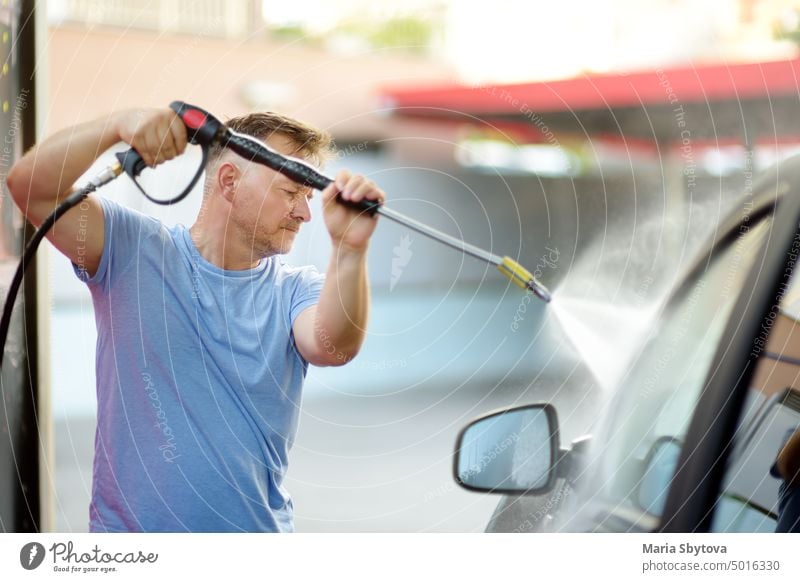 Car washing. Mature man cleaning automobile using high pressure jet water. self car use by himself carwash person spray glass service operation repair