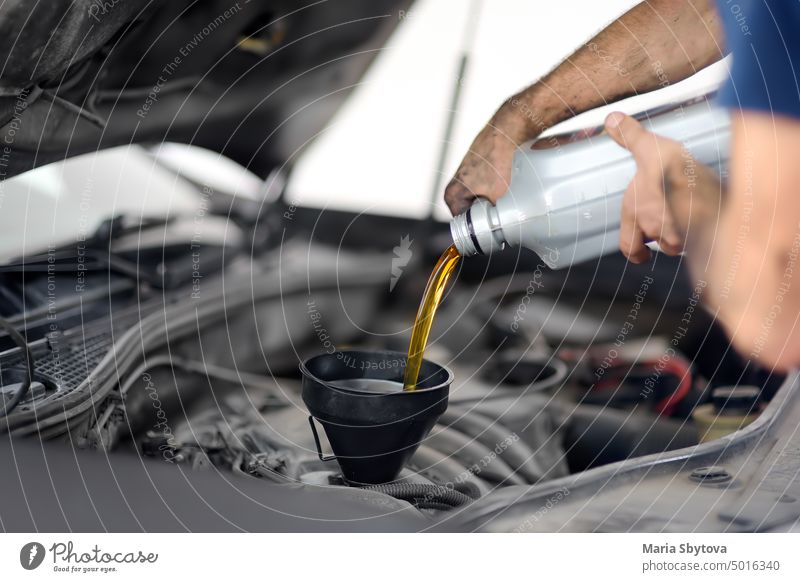 Man auto mechanic repairs car in autoservice, station. Changes oil. fresh lubricant change automobile garage operation motor maintenance servicing operational