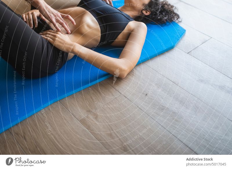 Instructor helping woman during yoga practice exercise breath trainer instructor fit together support wellness healthy correct female lying down personal asana