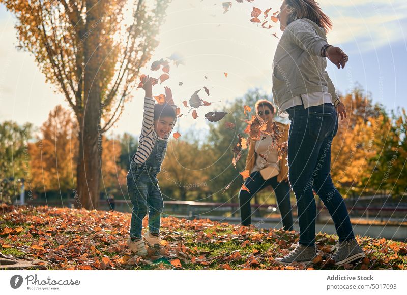 Carefree lesbian family with child playing in park lgbt couple having fun autumn weekend homosexual son together happy toss leaf foliage relationship smile