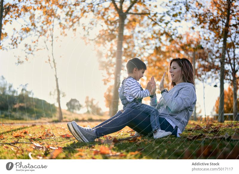 Mother and son playing clapping game in park mother child hand having fun playful autumn boy together kid happy cheerful love joy childhood fall nature little