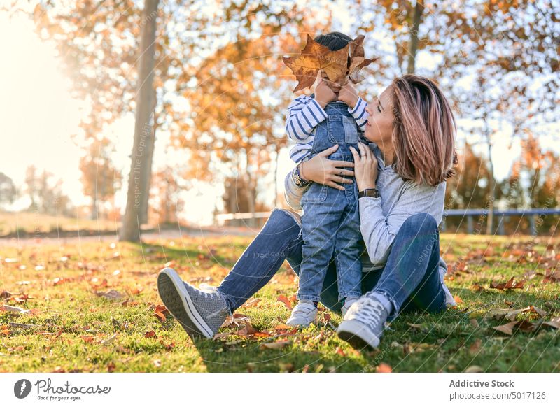 Content mother and child spending time in park autumn spend time son play together kid parent motherhood leaf fall having fun childhood love little family