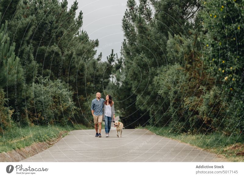 Delighted lovers hugging on footpath in wood with pet couple forest walk happy delighted dog casual wear road together romance leisure cheerful nature park