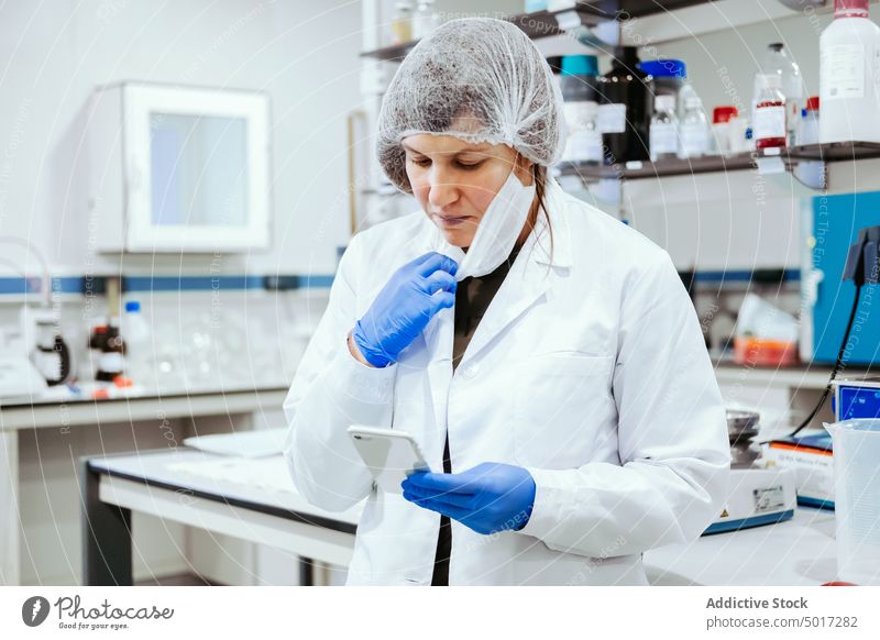 Serious chemistry using smartphone woman laboratory hospital serious adult doctor medicine healthcare break uniform technology device gadget browsing