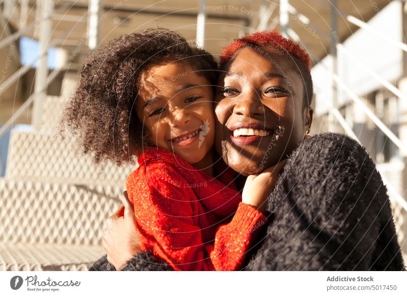 Smiling cute black girl embracing woman on steps mother street sunshine smiling cheerful child daughter stair sunny day african american happy positive walk