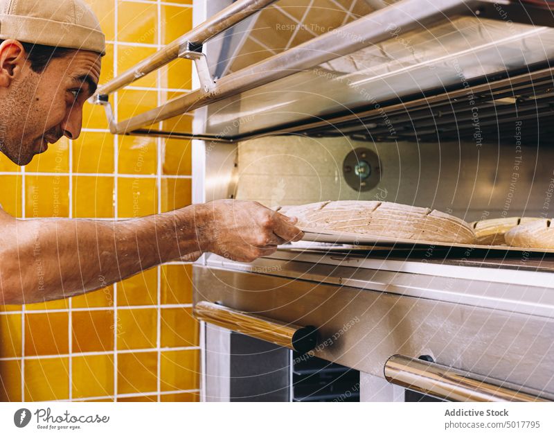 Man cooking bread in bakery oven man kitchen dough industrial male tray apron pastry prepare food fresh culinary work chef job uniform guy recipe occupation