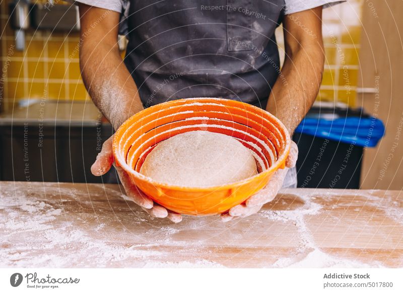 Crop male baker with dough in proofing basket raw man bread bakery kitchen prepare process fresh chef cuisine cook apron culinary table pastry stand guy flour